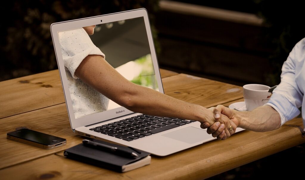 handshake through a computer screen symbolizing a digital marketing partnership